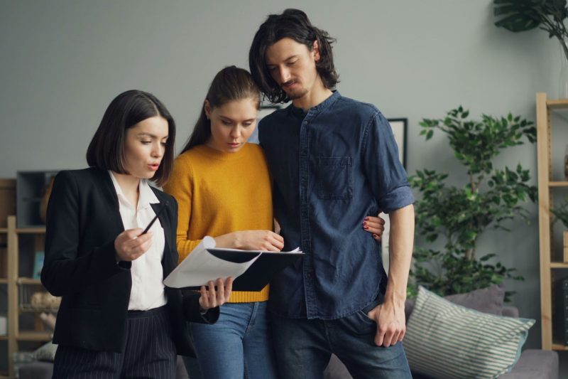 A couple reviewing documents with a real estate agent indoors
